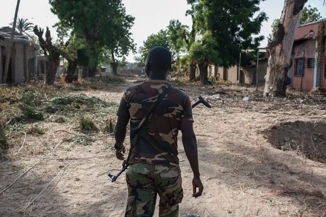 Nigerian soldier in damaged street