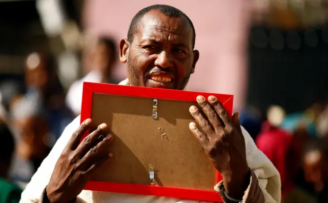 
          A man carries a photograph as he mourns her family members suspected to be missing following a landslide
        