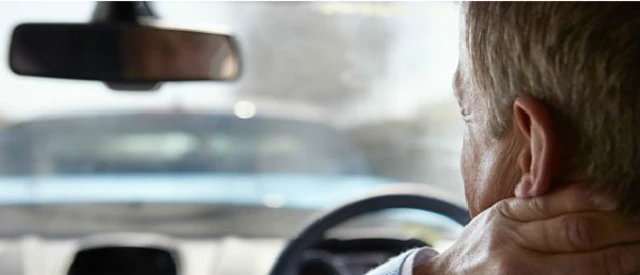 Man holding his neck in a car