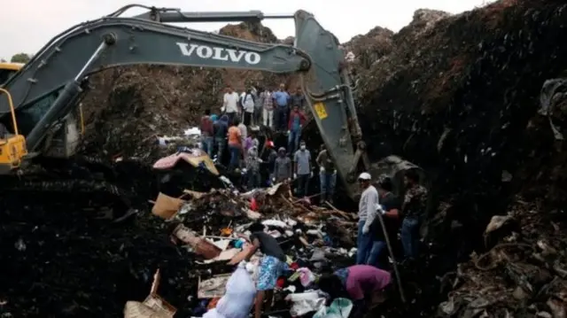 
          Rescue teams are using excavators to dig through piles of rubbish
        