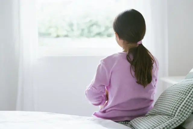 Young girl sitting on a bed