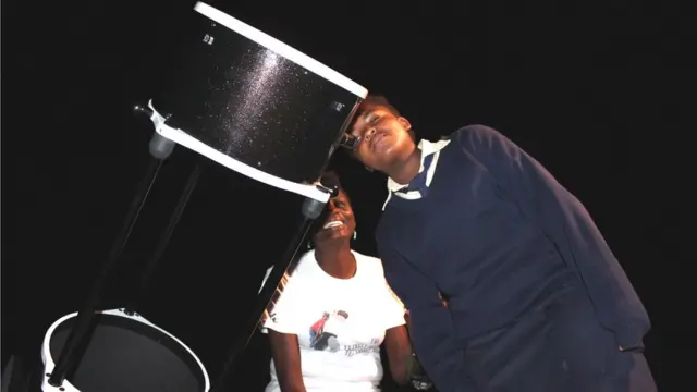 Students looks through giant telescope alongside