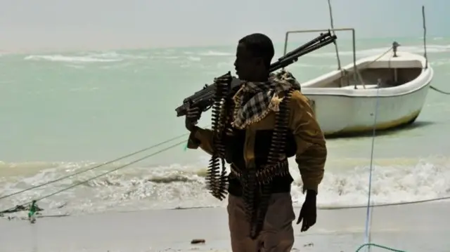 Somali pirate walks along a beach