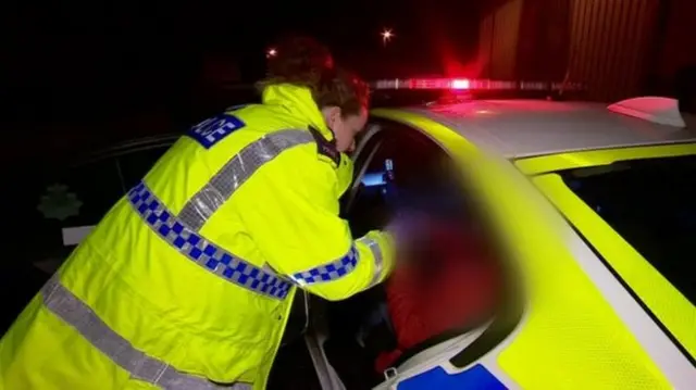 A police officer next to a police car