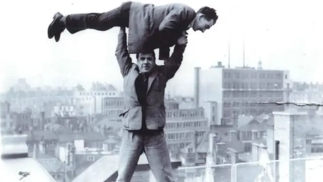 
          Fabian Cowan is lifted aloft by his friend Larry Miller during work on the Marks and Spencer building in Birmingham
        