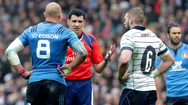 The referee talks to the two team captains