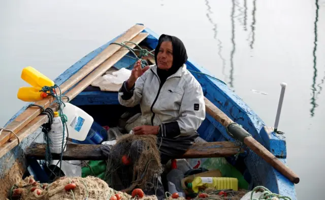 
          Chrifa Nimri, 69, a fisherwoman, arranges a net after returning to port in Sidi Bou Said, in Tunis
        