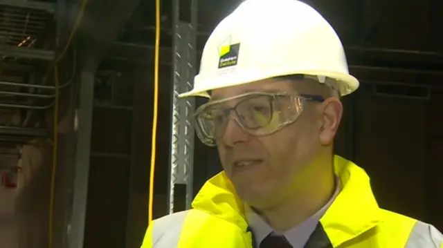 
          Nick Goodwin, in hard hat, protective glasses and yellow high viz jacket
        