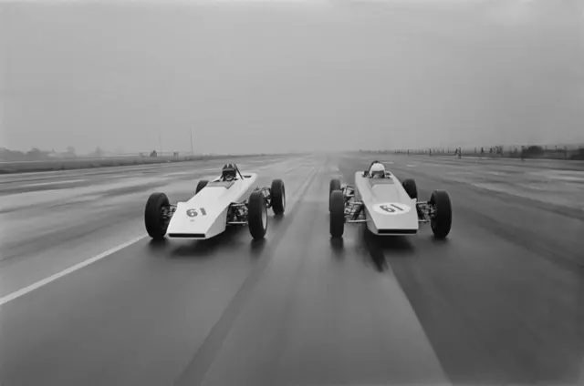 
          Black and white photo of the two racing cars on the racing circuit
        