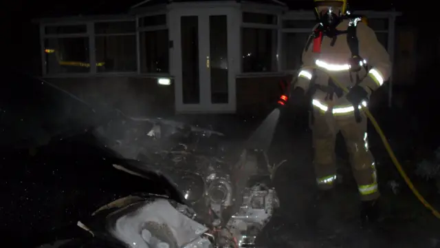 Firefighter using hose on car