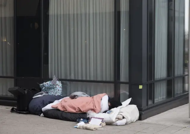 A homeless man sleeping near an office block