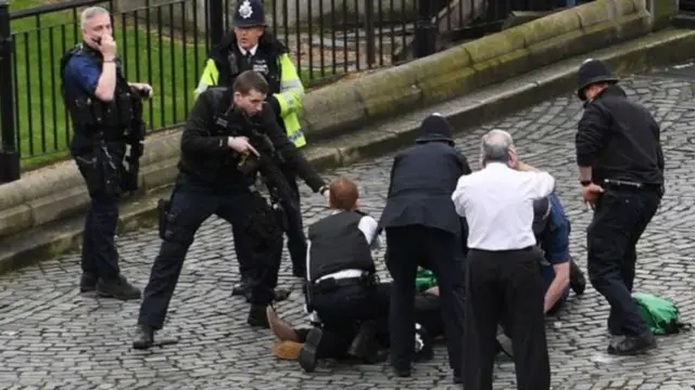 
          Armed police standing with gun over person on ground at Westminster
        