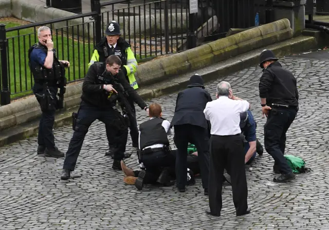 policeman points gun at man on floor