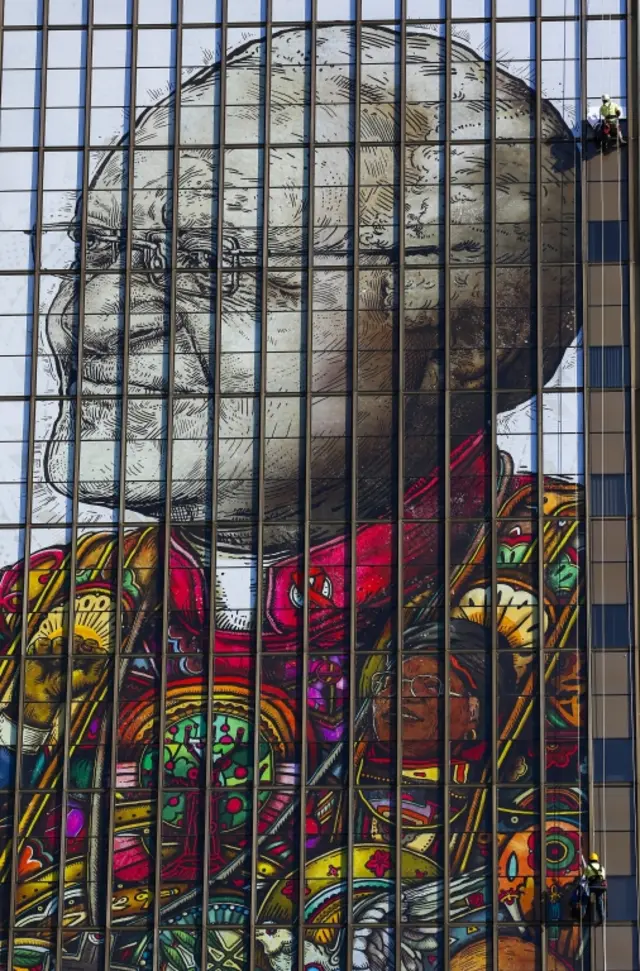 
          Workers install a giant image of Nobel Peace laureate Archbishop Emeritus Desmond Tutu on the side of the Civic Centre in Cape Town, South Africa 22 March 2017. The artwork by artist Linsey Levendal is in honour of Desmond Tutu and his wife Leah Tutu for their great sacrifices and contribution to South Africa and stands alongside one of former president Nelson Mandela
        