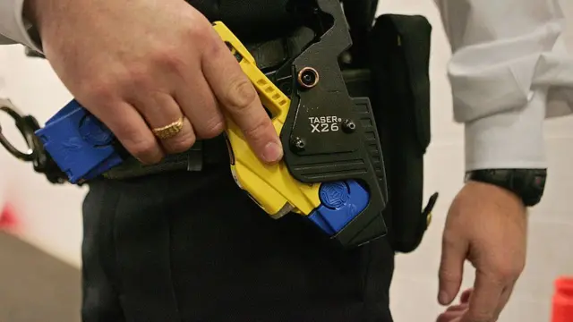 A British police officer holsters a taser gun