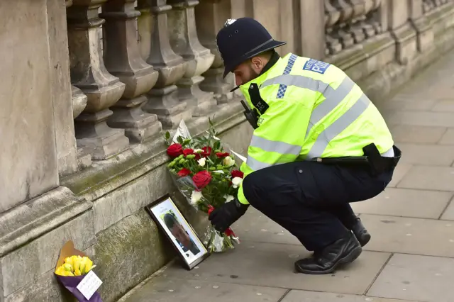 
          A police officer places flowers and a photo of PC Keith Palmer on Whitehall
        