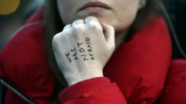 Girl with writing on her hand: 'We are not afraid'