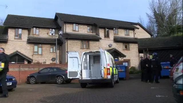 Police officers and open vehicle outside the properties