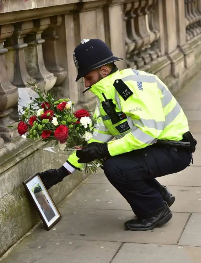 
          A police officer places flowers and a photo of PC Keith Palmer on Whitehall
        