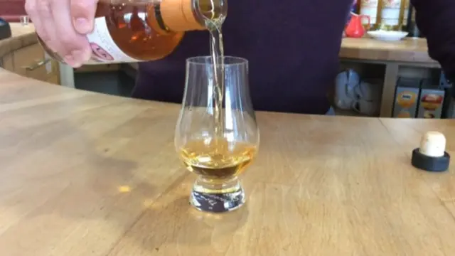 A male hand pouring whisky into a whisky glass