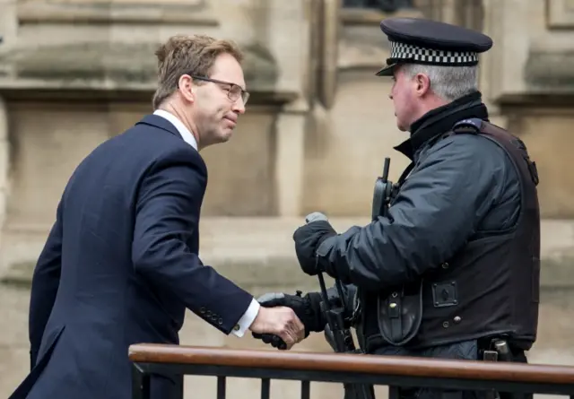 
          Police officer shakes Tobias Ellwood's hand outside Parliament on Friday
        