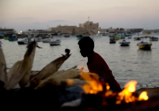 
          a vendor heats up a grill to roast corn on the Mediterranean Sea coast, in Alexandria, Egypt
        