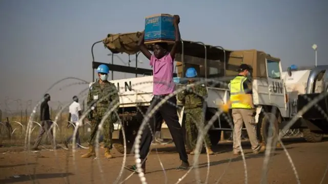 Boy carries provisions past UN blue helmets