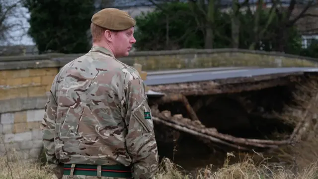 Soldier stands next to bridge