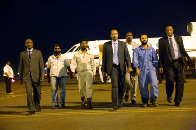 
          Sudanese officials walk with three foreign oil workers kidnapped by rebels in South Sudan after being released at Khartoum Airport, Sudan, March 30, 2017
        