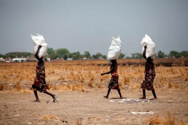 
          Three women carry a sack of food distributed on March 4, 2017, in Ganyiel, Panyijiar county, in South Sudan.
        