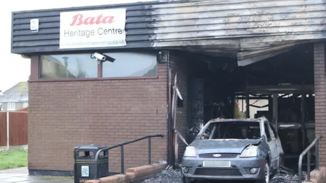 
          Smoke damaged building with the burnt out car still parked in the foyer
        