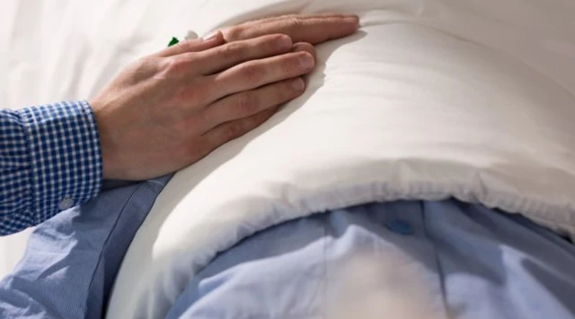 Man holding hand of patient in hospital bed