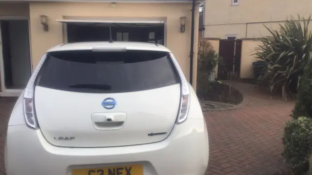 Electric car on driveway of house