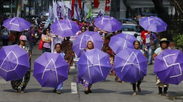 Women marching with purple umbrellas