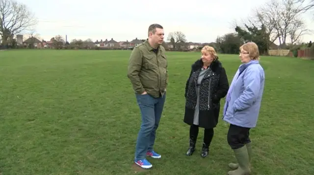 
          People who've signed the petition standing in the playing field
        