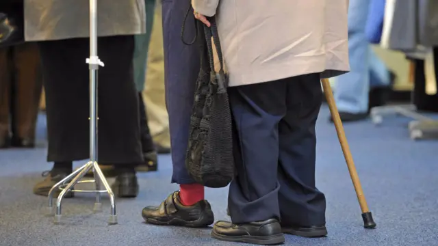 Generic picture of people with walking sticks in queue