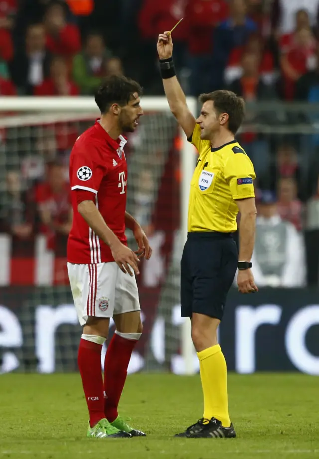 Javi Martinez is shown a yellow card by referee Nicola Rizzoli