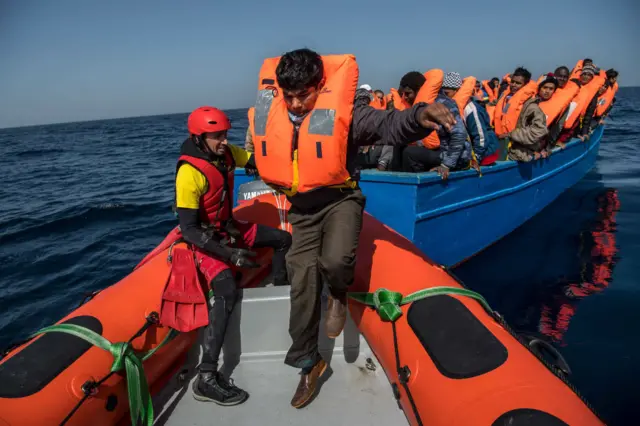 People being helped off a boat