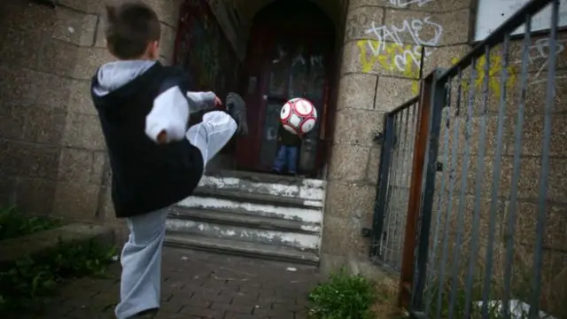 Child kicking a football up a close