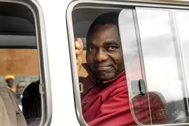 Zambian opposition leader Hakainde Hichilema waves to supporters from a police van as he leaves a courtroom in Lusaka on April 18, 2017.