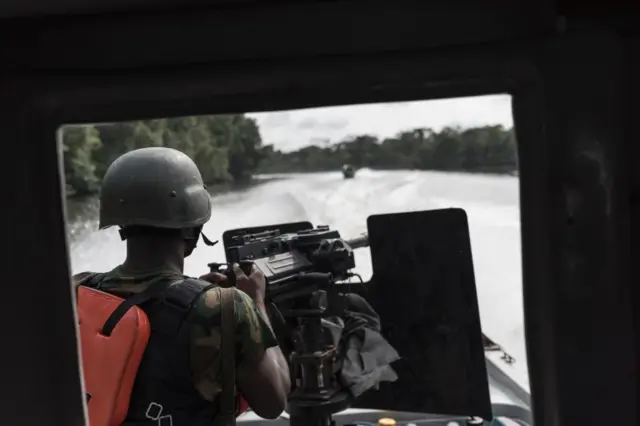 A Nigerian soldier on the back of a gun boat surveys a creek for illegal oil refineries during a patrole on April 19, 2017 in the Niger Delta region near the city of Warri. Nigerian forces are cracking down on illegal oil refineries in the countrys oil heartland