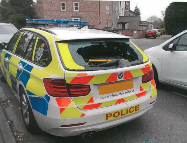 Police car with rear window smashed.