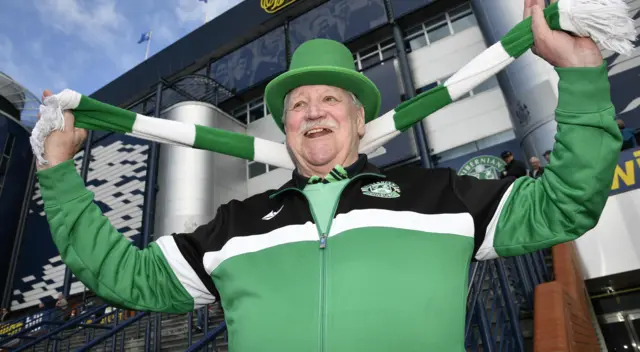 A Hibs supporter holds his scarf aloft