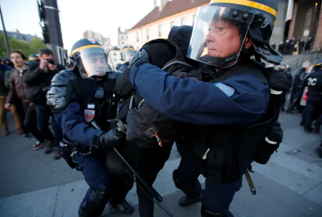 French riot police apprehend a demonstrator during clashes in Paris after early results in the first round of 2017 French presidential election are announced, 21 April 2017