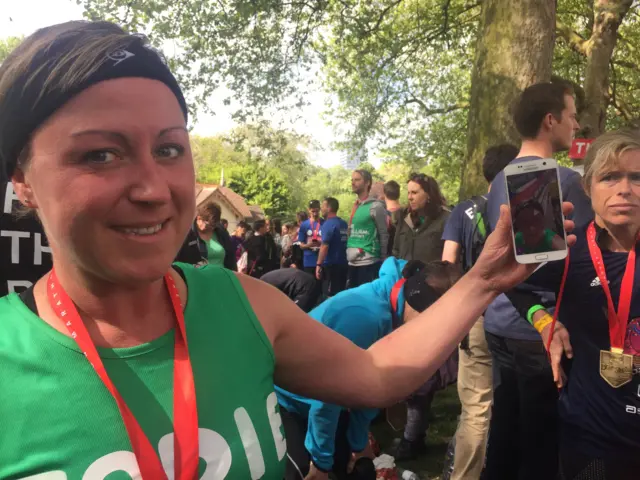 Jodie holding her phone after completing the London Marathon