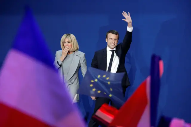 Emmanuel Macron, flanked by his wife Brigitte Trogneux, speaks after projected results suggest that he has won the first round of the elecion