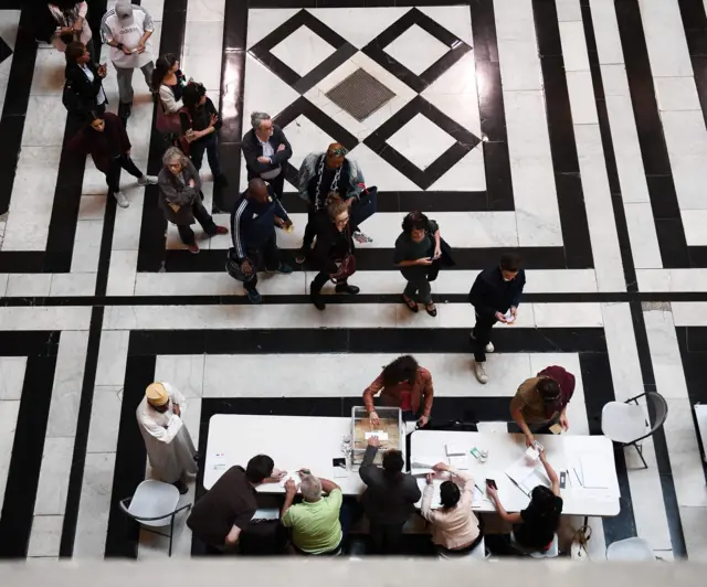 seen from above, a queue to a ballot table, with ornate tiled floor