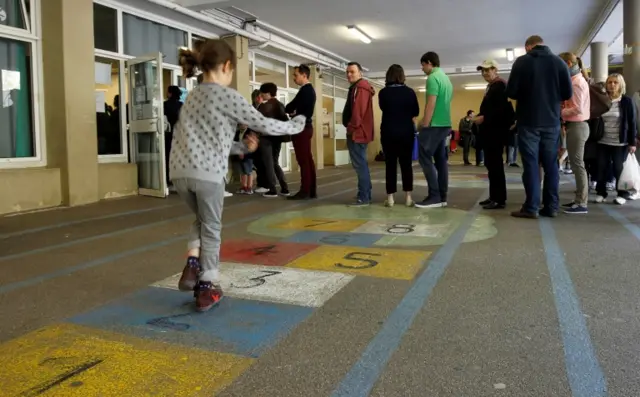 A girl plays hopscotch as voters queue in Marseille