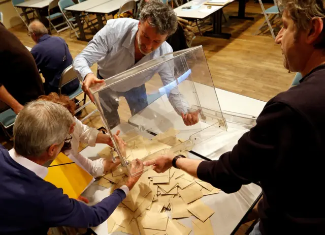 Officials empty a ballot box at the start of counting in the first round of 2017 French presidential election, at a polling station in Tulle,