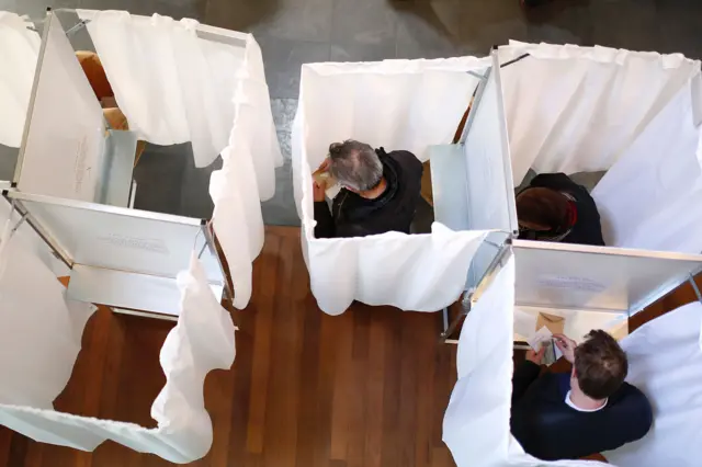 Voters pick their candidates at a polling station in Paris, 23 April 2017